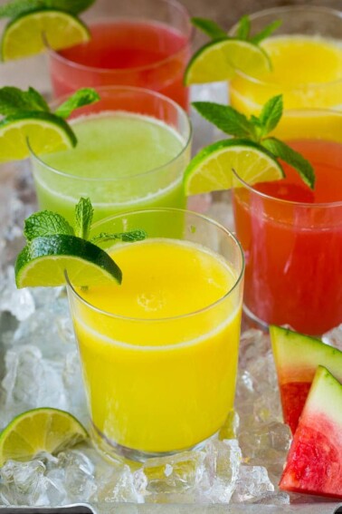 Cups of agua fresca in assorted fruit flavors.