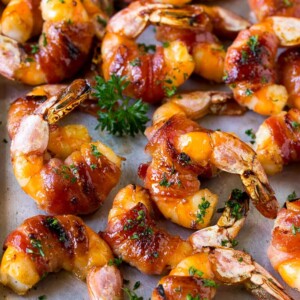 Bacon wrapped shrimp in a sweet and savory glaze, garnished with parsley.