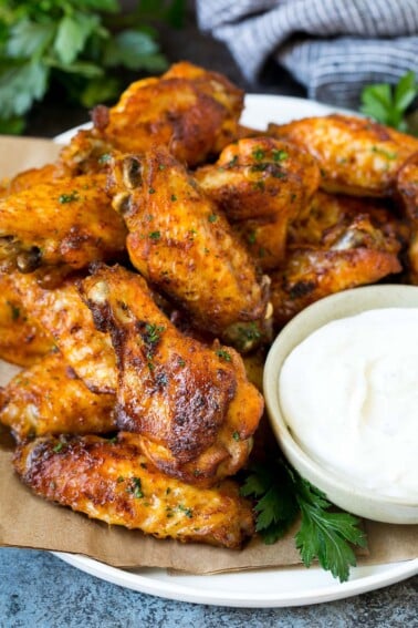 A plate of baked chicken wings served with ranch dip.