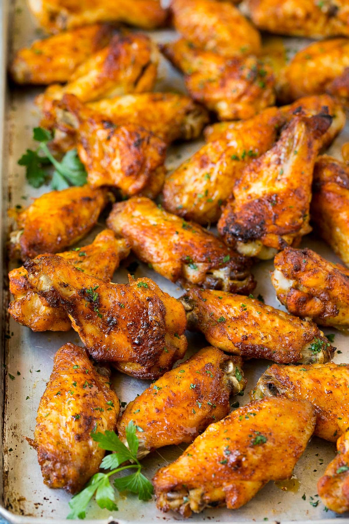 A tray of baked chicken wings garnished with parsley.