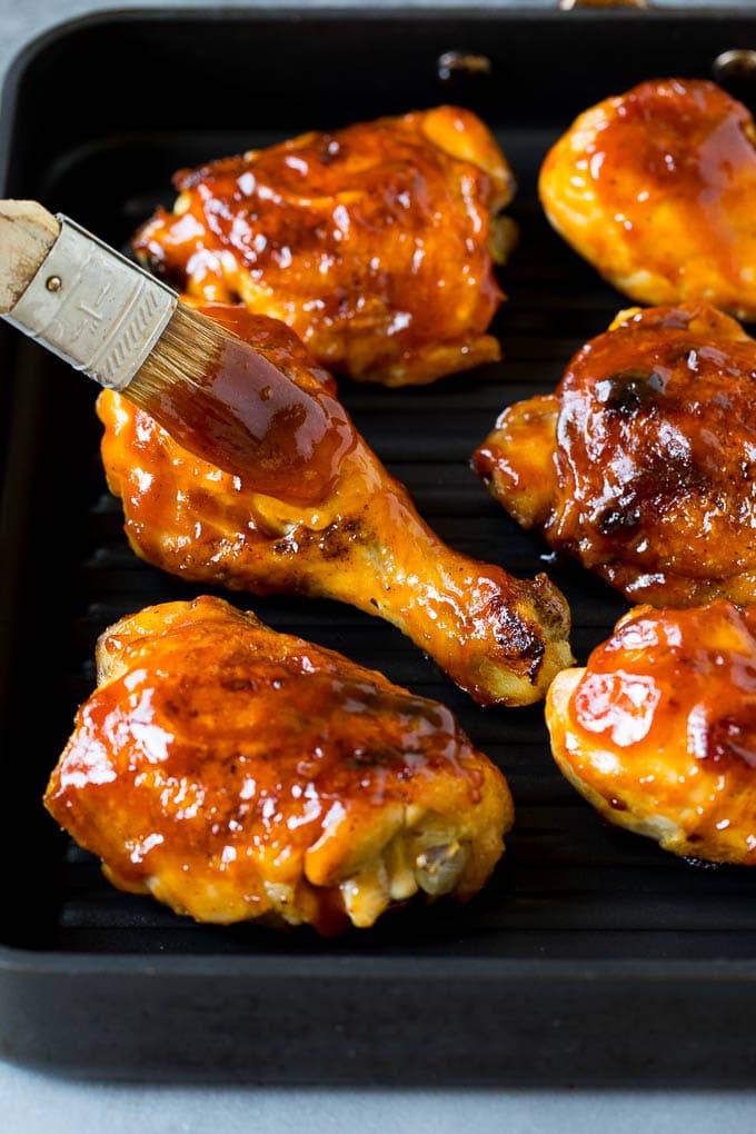 Barbecue sauce being brushed over grilled chicken.