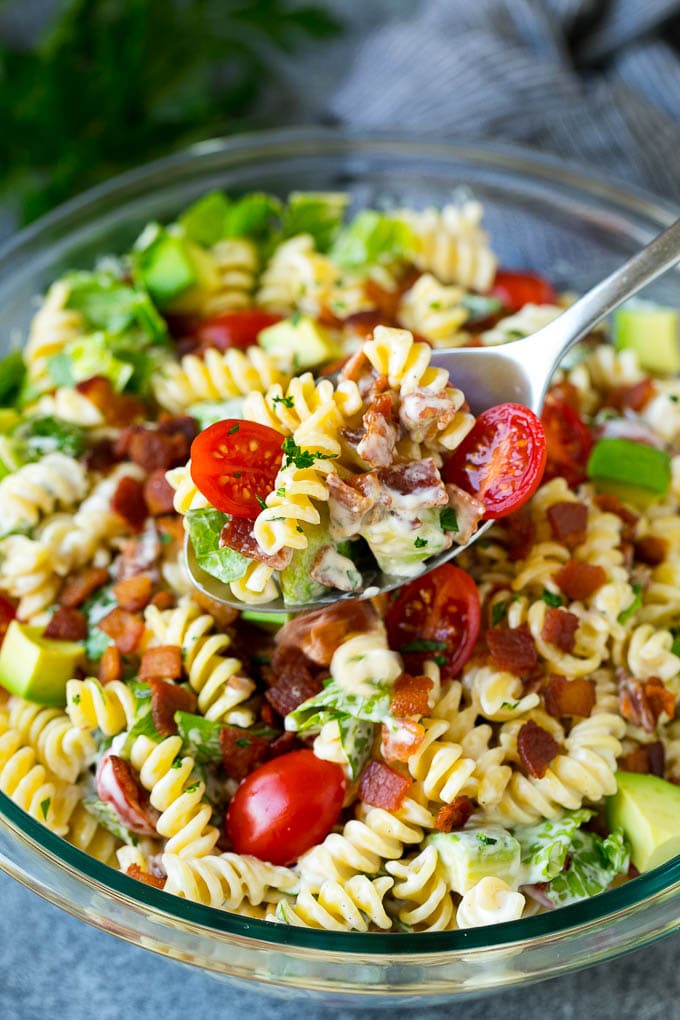 A serving spoon filled with BLT pasta salad.