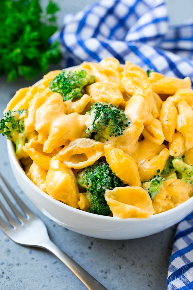 A bowl of broccoli mac and cheese with shell pasta, cheddar and broccoli florets.