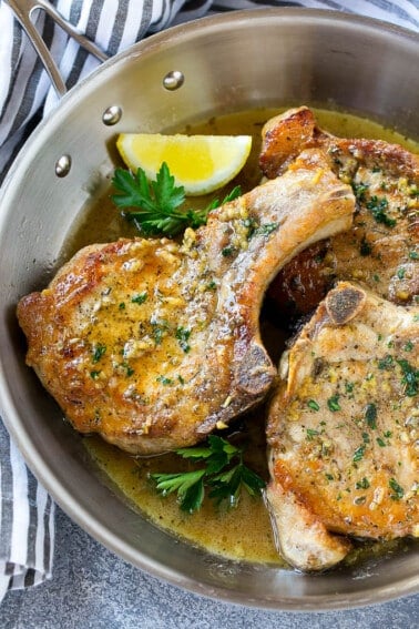 Brown sugar pork chops with garlic, butter and herbs in a frying pan.