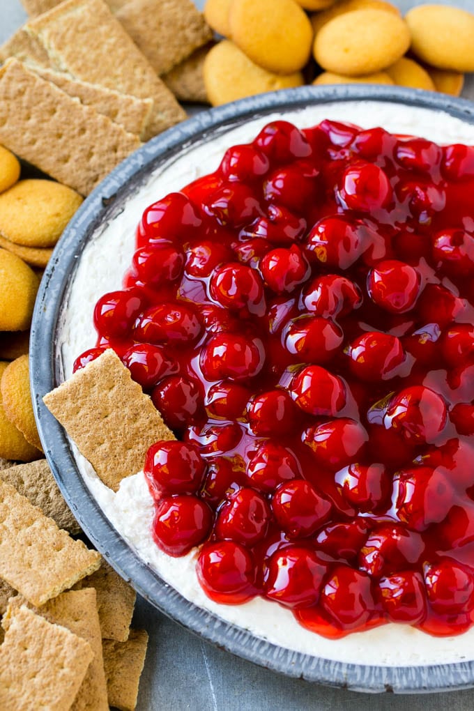 A plate of cherry cheesecake dip with a graham cracker in it.