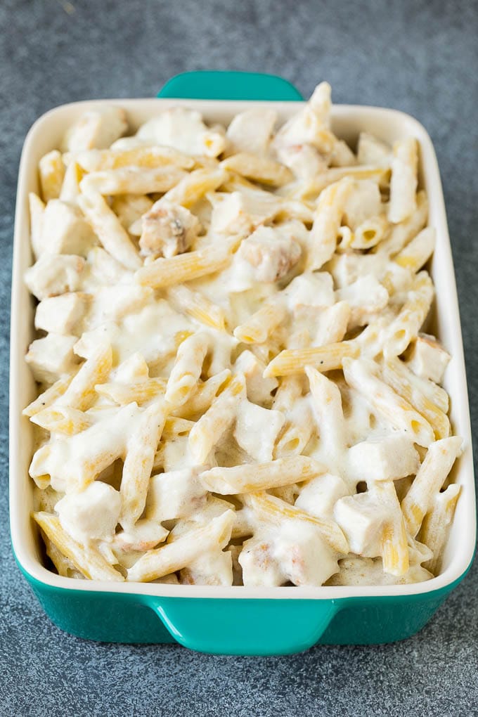 Penne tossed with Alfredo sauce in a baking dish.