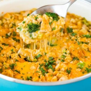 A spoon serving up a portion of cheesy chicken broccoli casserole.