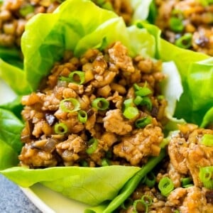 Chicken lettuce wraps on a serving plate, garnished with green onions.