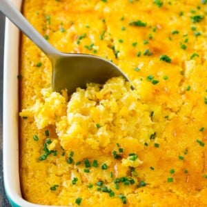 A pan of corn pudding with a serving spoon in it.