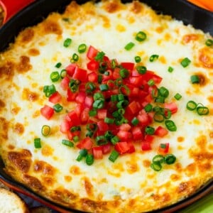 Hot crab dip in a skillet topped with tomatoes and green onions.