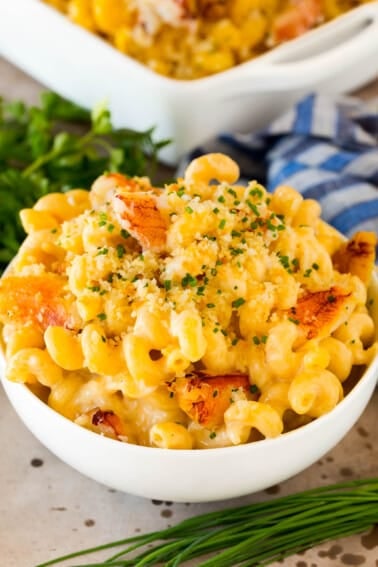 A bowl of crab mac and cheese topped with herbs.