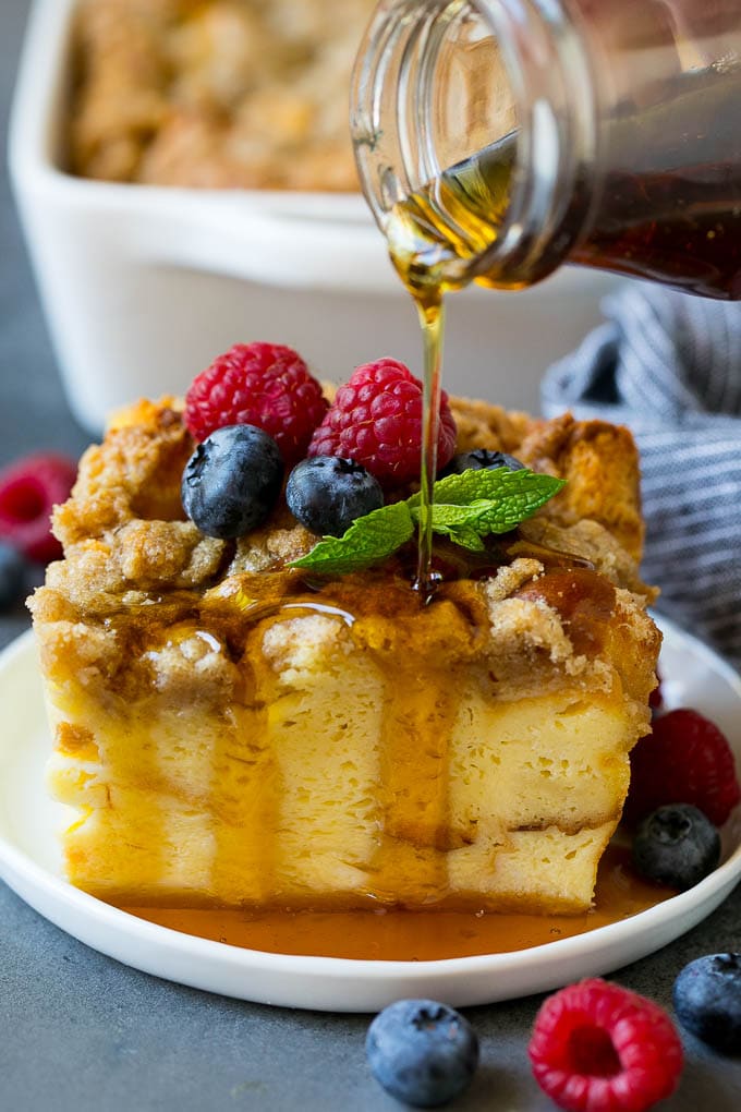 A piece of french toast casserole with syrup being poured over the top.
