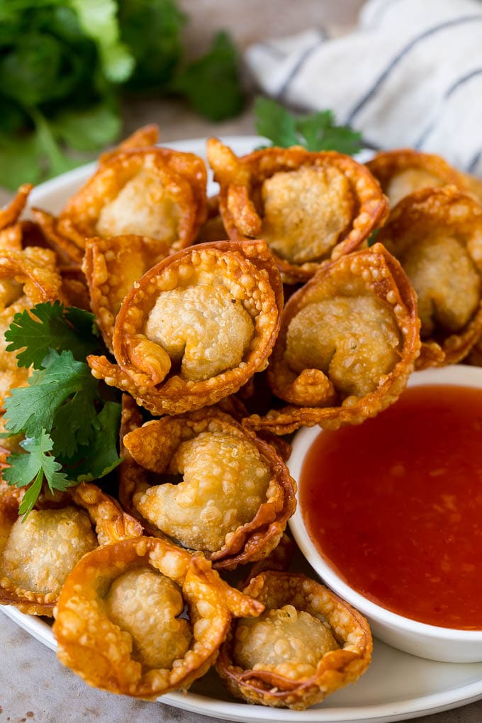 A plate of fried wonton served with sweet chili sauce.