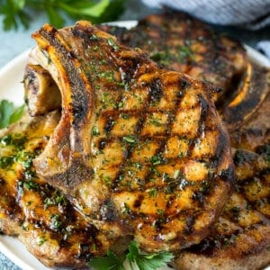 Grilled pork chops coated in marinade then cooked and garnished with parsley.
