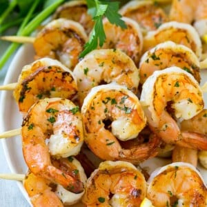 Grilled shrimp skewers with lemon wedges and parsley.