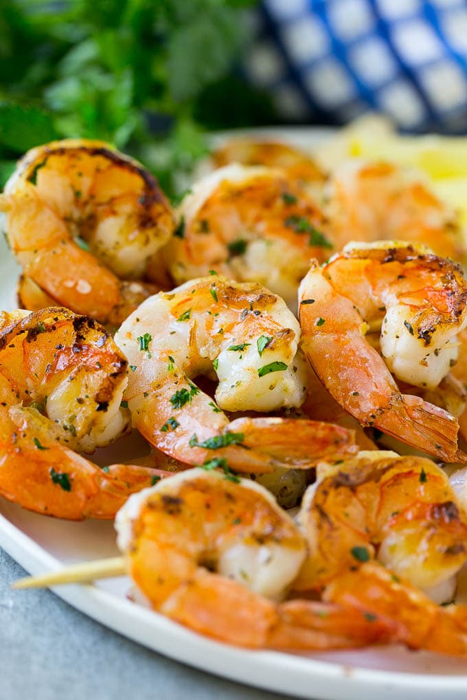 Shrimp threaded onto skewers and grilled, then garnished with chopped herbs and lemon juice.