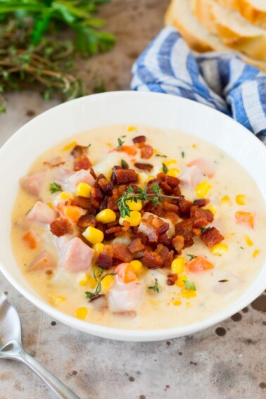 A bowl of ham and corn chowder garnished with bacon.