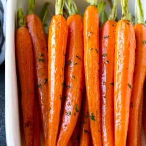 Honey roasted carrots in a baking dish, garnished with chopped parsley.