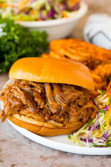Instant Pot pulled pork on a sandwich with a side of fries and coleslaw.
