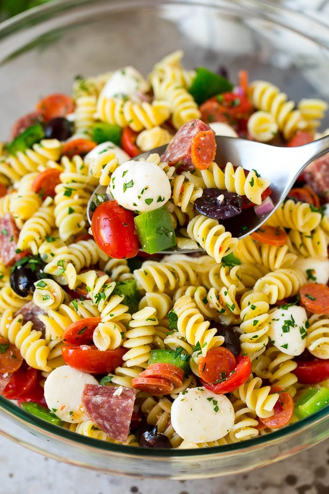A serving spoon in a bowl of Italian style pasta salad.