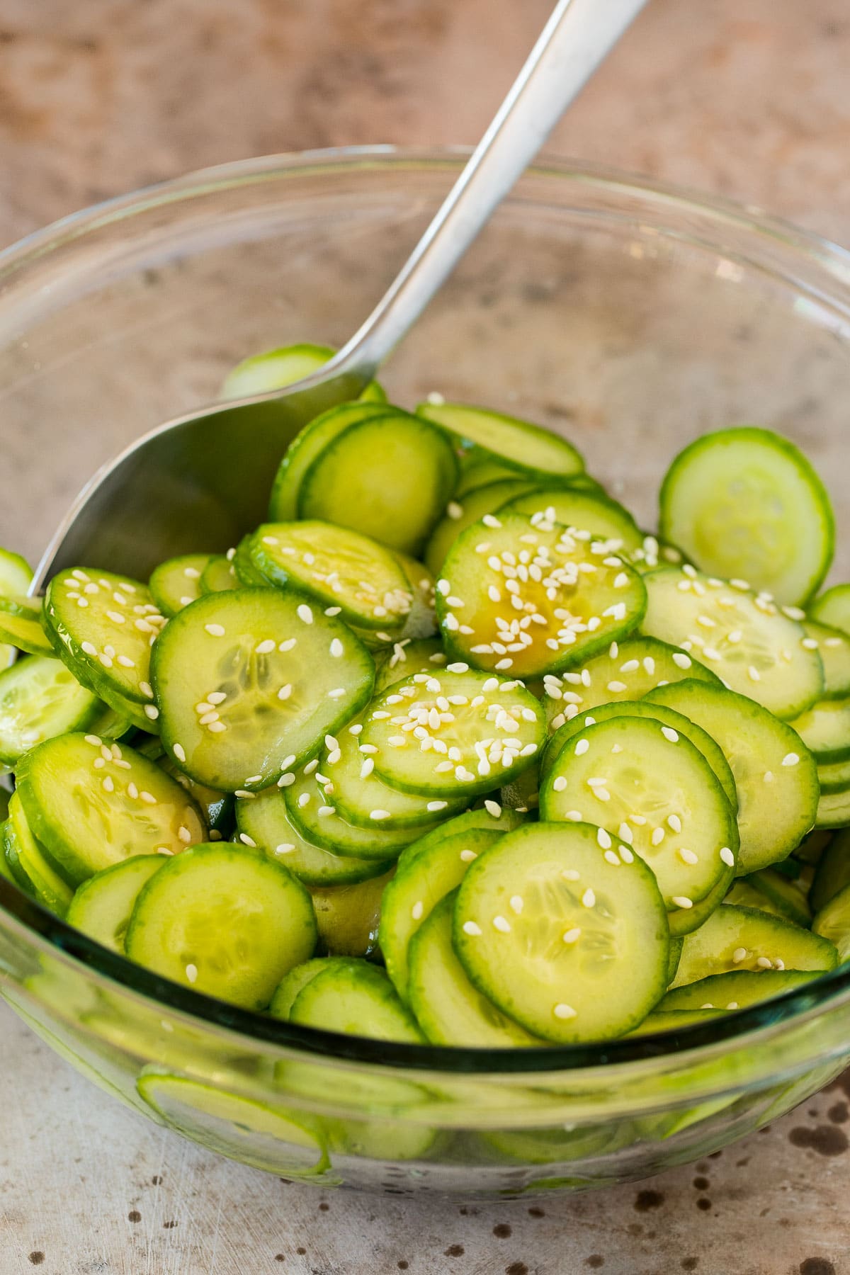 A bowl of cucumbers in dressing, topped with sesame seeds.