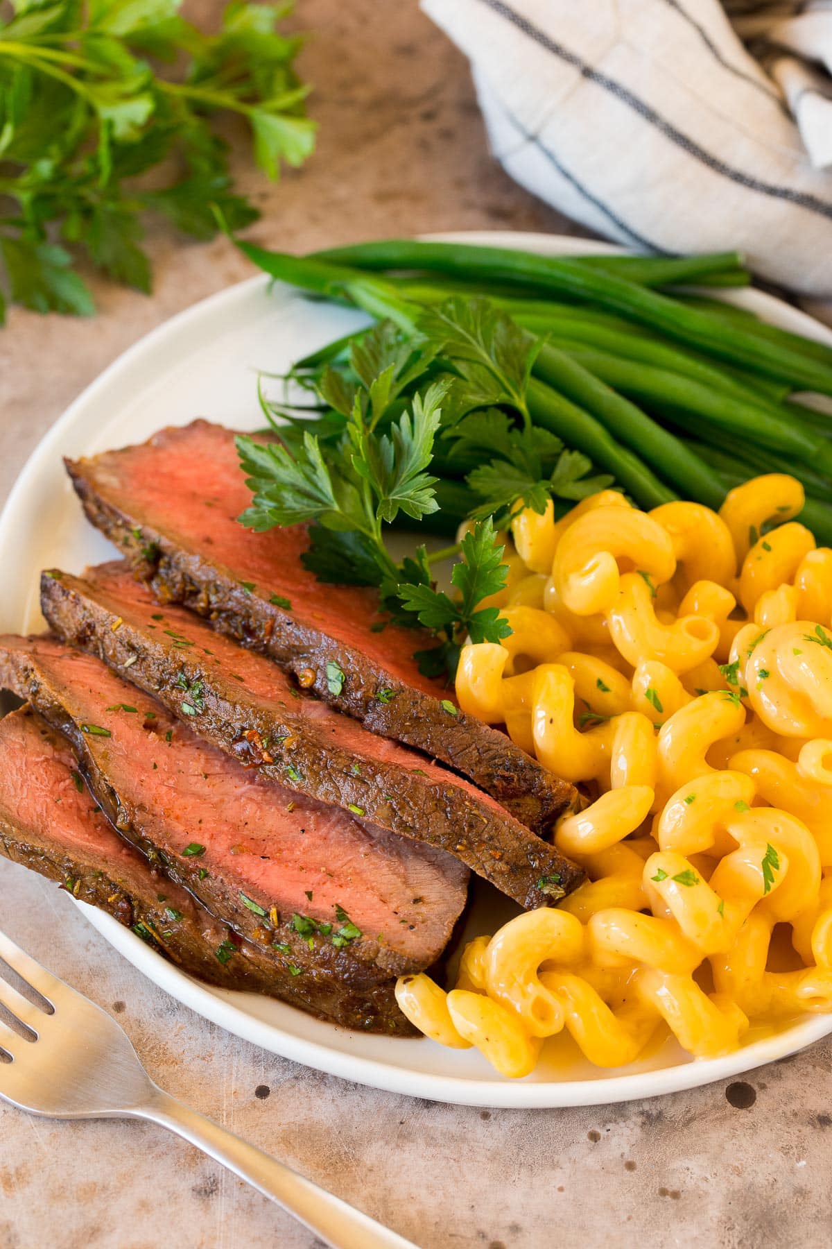Sliced London broil served with mac and cheese and green beans.