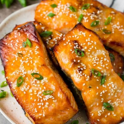 A platter of miso salmon fillets topped with sesame seeds and green onions.