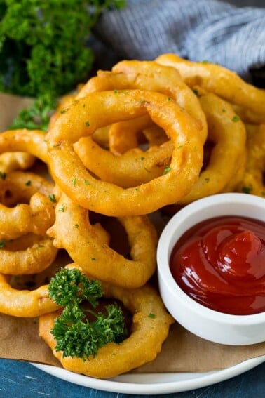 Fried onion rings on a plate with a side of ketchup.