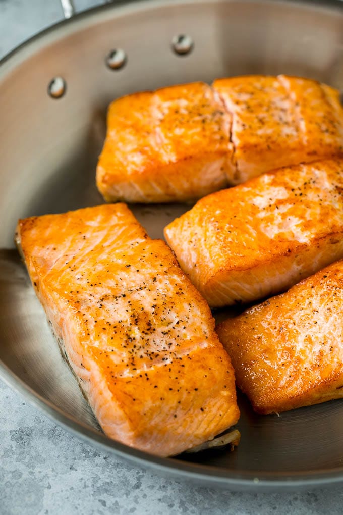 Sauteed salmon fillets in a metal skillet.