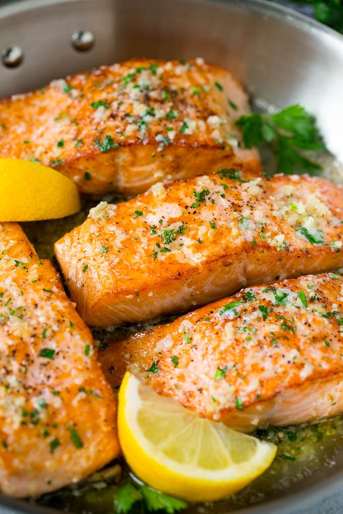 A pan of seared salmon in a butter sauce.