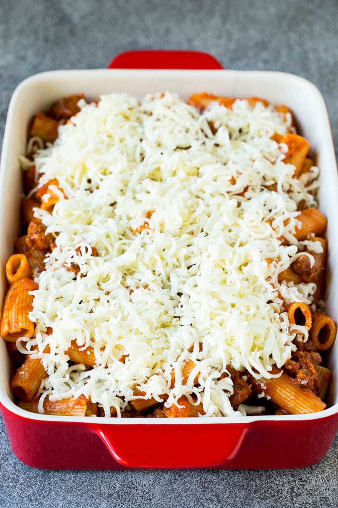A dish of rigatoni tossed in meat sauce and topped with shredded cheese.