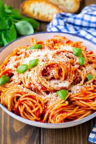 A serving bowl of pasta pomodoro garnished with fresh basil.