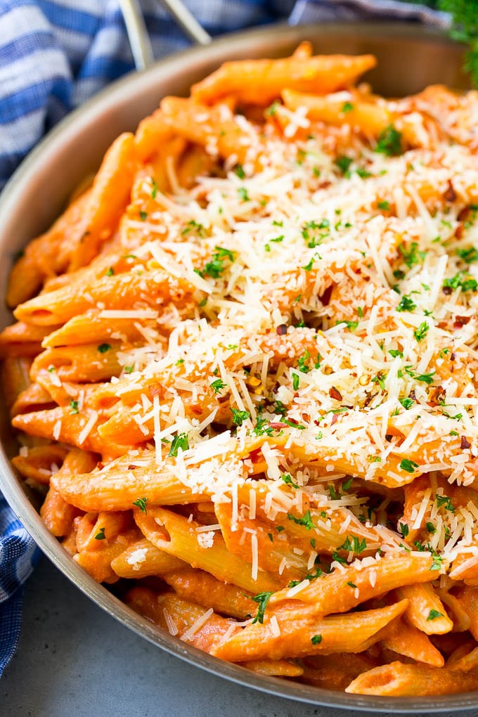 A skillet of penne alla vodka topped with shredded parmesan cheese.