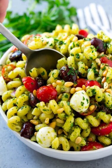 Pesto pasta salad with cherry tomatoes, olives, mozzarella balls, pine nuts and red onion.