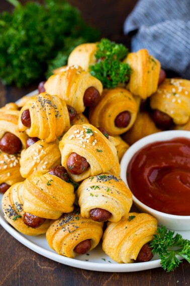 A plate of pigs in a blanket served with ketchup.
