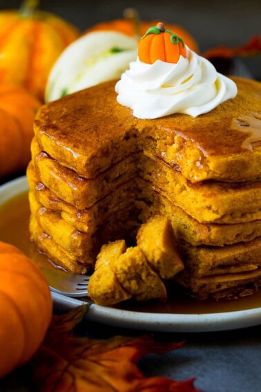 A stack of pumpkin pancakes with a fork holding cut pieces of pancake.