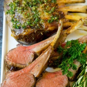 A platter of rack of lamb garnished with fresh herbs.