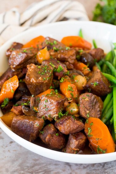 Slow cooker beef bourguignon in a bowl served with green beans.