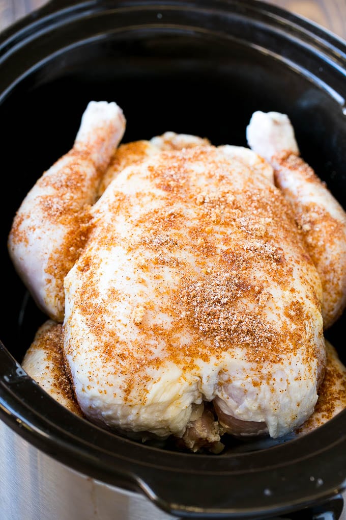 A whole chicken in a slow cooker ready to be cooked.
