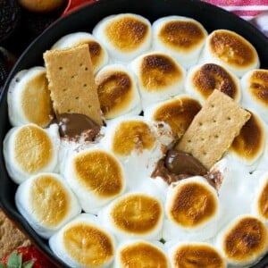 A skillet of s'mores dip with melted milk chocolate topped with toasted marshmallows.
