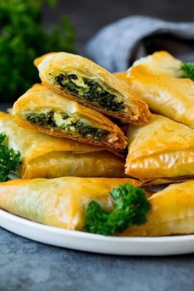A plate of spanakopita with two cut in half.