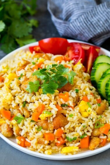 A plate of Thai fried rice garnished with cucumbers and tomatoes.