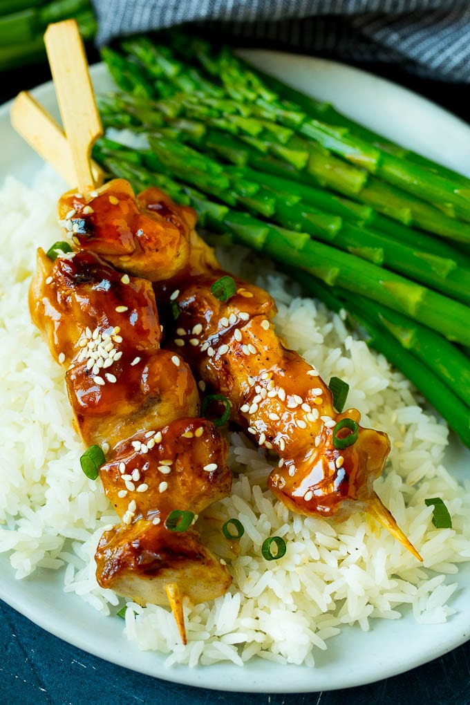 Yakitori skewers served over steamed rice with asparagus.